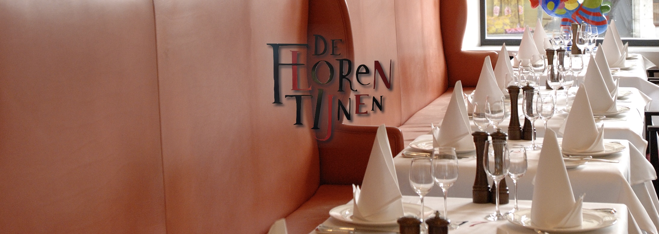 Restaurant De Florentijnen: gedekte tafels met witte linnen servetten naast een terracotta lederen banquette